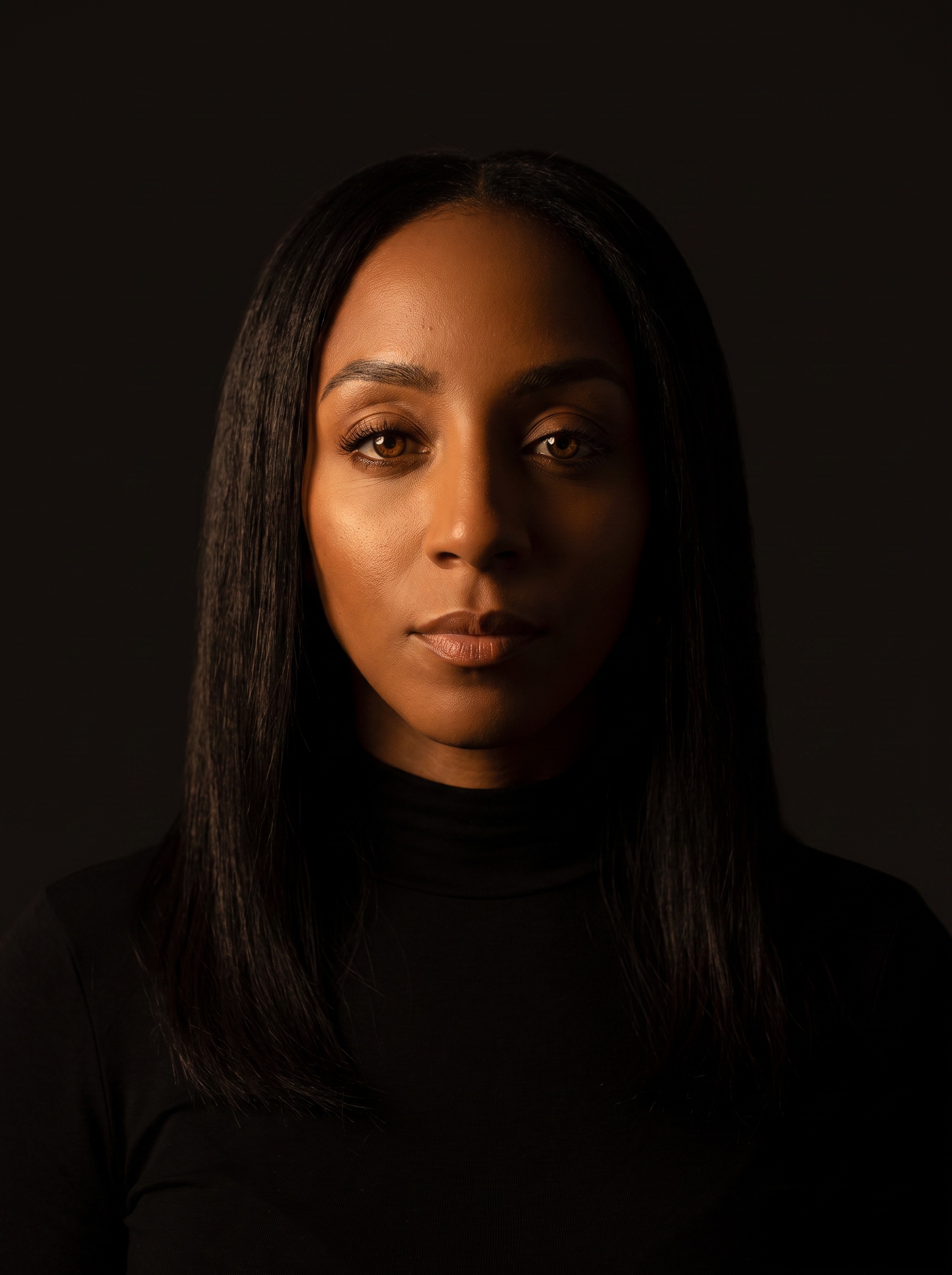 Dramatic portrait of Markesha against a dark background, calm and direct.